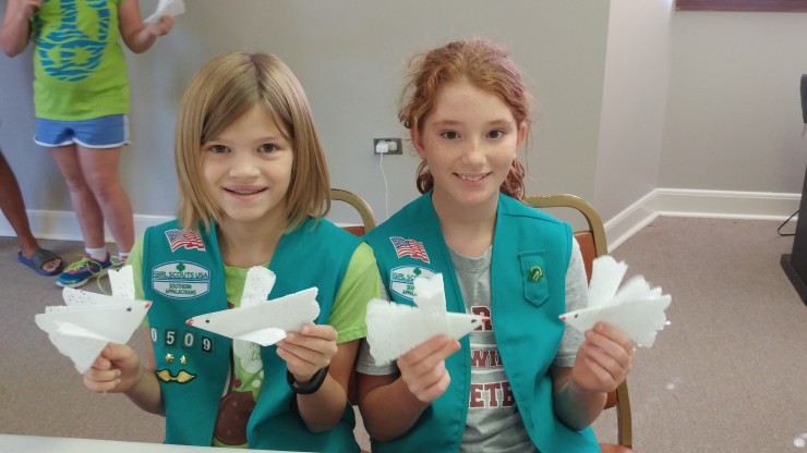 Becca Seay, right, and Daphne Seay, left, Junior Girl Scouts from Troop 20508 fold white peace doves as souvenirs of the Girl Scouts celebration of the UN's International Day of Peace. (Submitted photo)