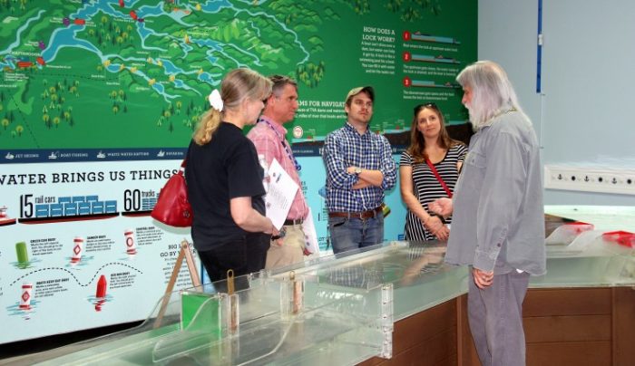 Kristine Torrance, left, David Torrance, and David Bush, both with the TVA Norris Engineering Laboratory, and Ashley Zeringue and Bucky Smith, with the Childrenâ€™s Museum, gather around the model of TVA locks and dams on the Tennessee River in the Waterworks exhibit. (Submitted photo)
