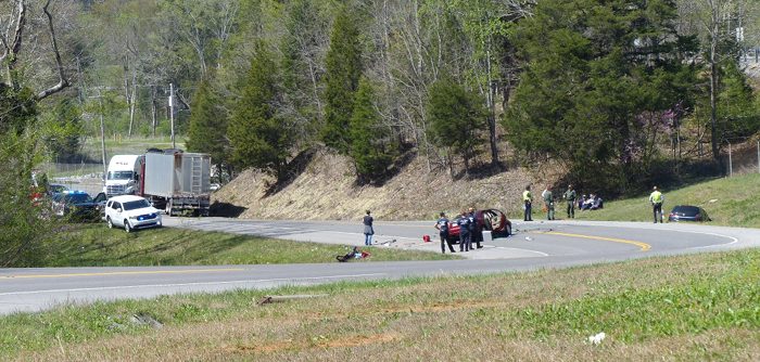 A driver died after a crash on State Route 95 near the entrance to the TRU Waste Processing Center north of Interstate 40 on Monday afternoon, April 10, 2017. One vehicle, the dark-colored Saturn Astra at right, went off the road. A second vehicle, the red Mercury Sable in the middle of the road, was reported to have crossed the center line and hit a truck trailer, pictured down the hill at left. The TRU Center is up the hill to the right. This picture is taken facing north. (Photo by John Huotari/Oak Ridge Today)