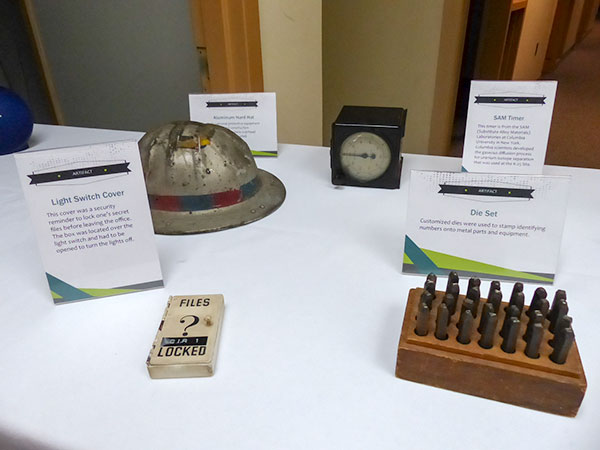 Artifacts are pictured above at the K-25 History Center on Thursday, Oct. 19, 2017. Among them are an aluminum hard hat, a timer, a light switch cover, and a die set. (Photo by John Huotari/Oak Ridge Today)