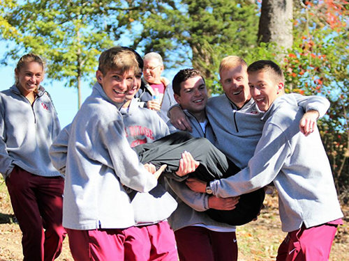 The Oak Ridge boys cross country team carries Coach Ed Wright, who took a swim in the pond at Victor Ashe Park in Knoxville on Thursday, Oct. 26, 2017, after the Wildcats' boys and girls cross country teams both qualified for the state meet in Nashville on Saturday, Nov. 4. The swim is a tradition when both teams win the regional meet, and it was amended this year "just so I would take a swim," Wright said, after the boys and girls teams both finished third and qualified together for state for the first time since 2014, in the Region 2 Large Division Championships at Victor Ashe Park on Thursday. (Photo by Maddie Zawisza)