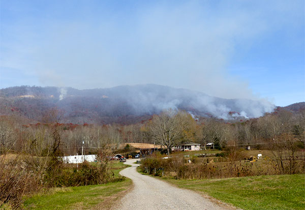 The forest fire reported on Big Brushy Mountain between Oliver Springs and Petros on Sunday, Nov. 26, 2017, grew to 300 acres, and it was reported to have containment lines around it on Tuesday, Nov. 28. The fire is pictured above from State Route 62 near Back Petros Road on Monday, Nov. 27. (Photo by John Huotari/Oak Ridge Today)