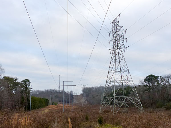 This picture shows a larger steel lattice tower to the right and a smaller H tower to the left near the intersection of Wilberforce Avenue and South Benedict Avenue between the Scarboro neighborhood, which is to the right, and the Oak Ridge Baseball Complex to the left. This picture is looking south toward Pine Ridge. The Y-12 National Security Complex is over the ridge. (Photo by John Huotari/Oak Ridge Today)
