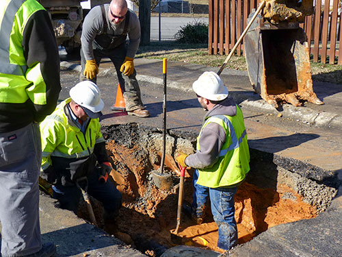 The Oak Ridge Public Works Department crew pictured above repairing a broken six-inch water line under Northwestern Avenue on Saturday, Jan. 6, 2018, is, standing on pavement, Joey Wheeler, equipment operator, and in hole, Gene Wilson, water specialist, left, and Jeremy Justice, maintenance mechanic. (Photo by John Huotari/Oak Ridge Today)