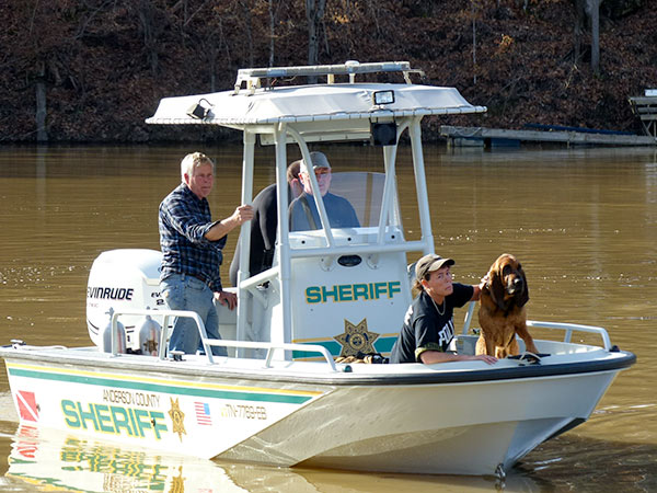 Rescuers in an Anderson County Sheriff's Department boat search for a missing man in the water at Bull Run Park in Claxton, authorities said Sunday afternoon, Feb. 18, 2018. Anderson County Sheriff Paul White is at left in the boat. In front is Knoxville Police Department search and rescue volunteer Candy Stooksbury with K-9 Barnabas, a bloodhound. (Photo by John Huotari/Oak Ridge Today)