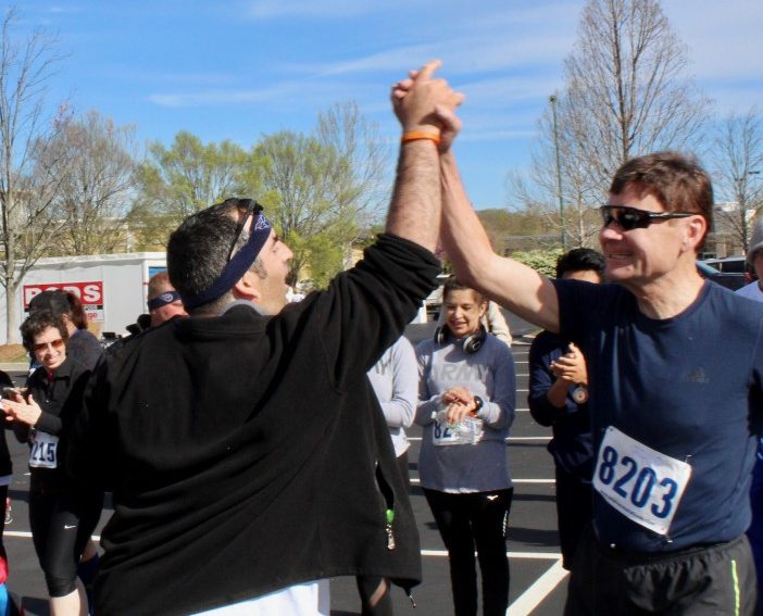 Joe Judkins, right, of Oak Ridge, gets a high-five from Seth Krichinsky, an adult with autism who cheers on participants and helps hand out awards. Judkins came in first in his age group in the 5K run last year. (Submitted photo)