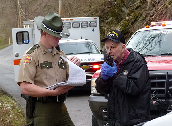 Pictured above investigating a fatal single-vehicle crash in Poplar Creek along Poplar Creek Road in Roane County late Tuesday morning, March 20, 2018, are Tennessee Highway Patrol Trooper James Capps, left, and Roane County Medical Examiner Thomas Boduch. (Photo by John Huotari/Oak Ridge Today)
