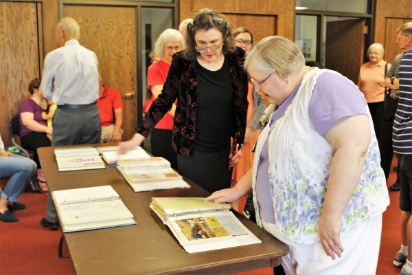 Oak Ridge Public Library Director Kathy McNeilly, center, chats with guests at her retirement celebration on Friday, June 15, 2018, as they look over scrapbooks of library history. (Photo by City of Oak Ridge)